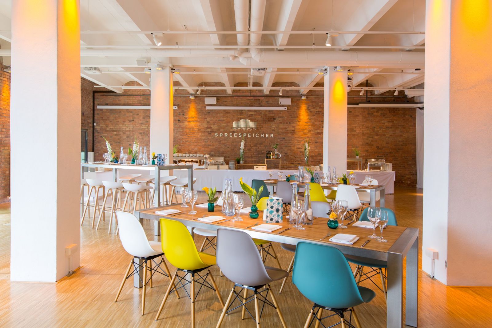 030 Eventloft Medio mit Tafeln, bunten Stühlen und Buffet vor der Backsteinwand