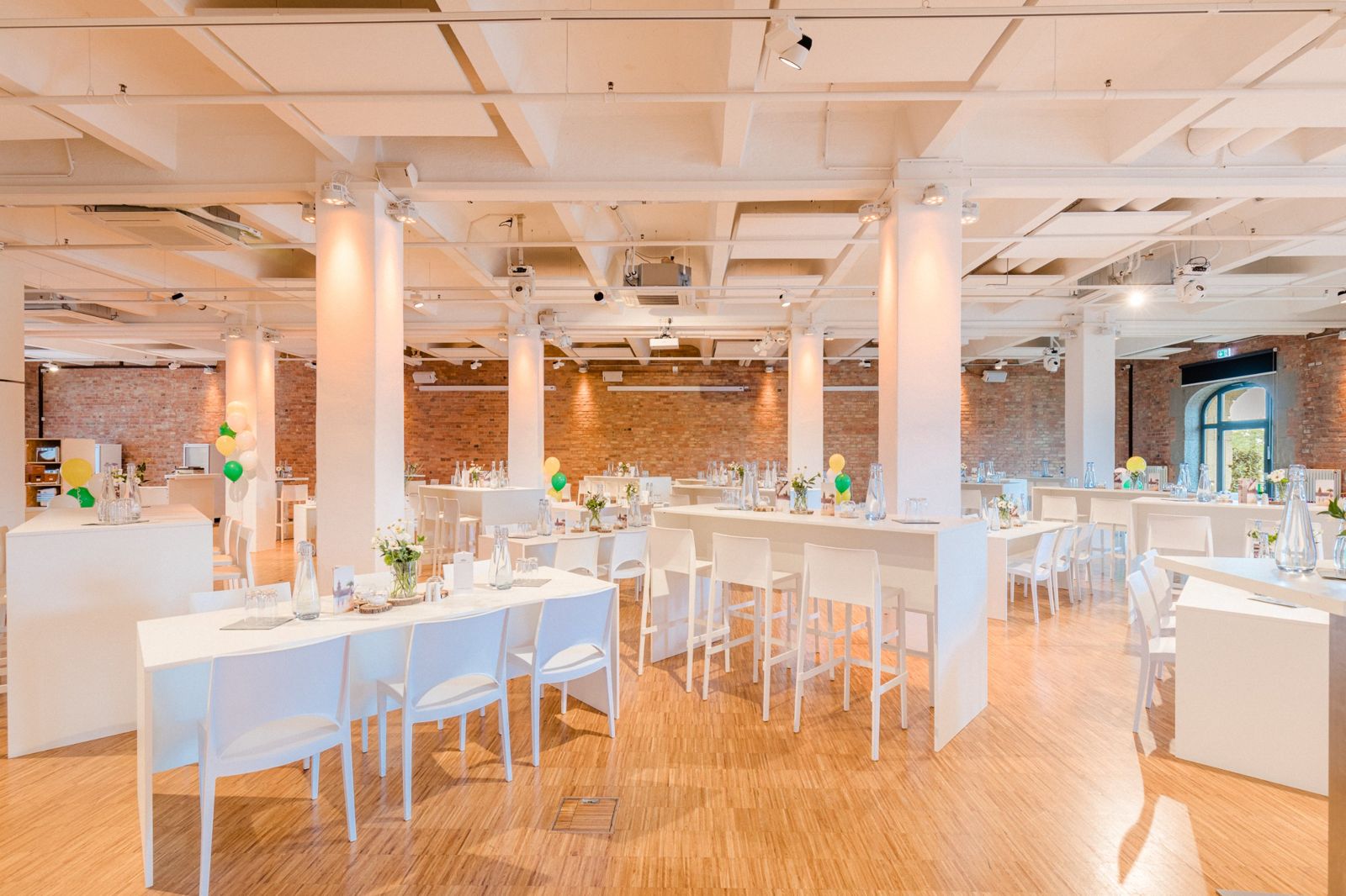 030 Eventloft Grande mit Tafeln, Stehtischen und bunten Ballons vor Backsteinwänden
