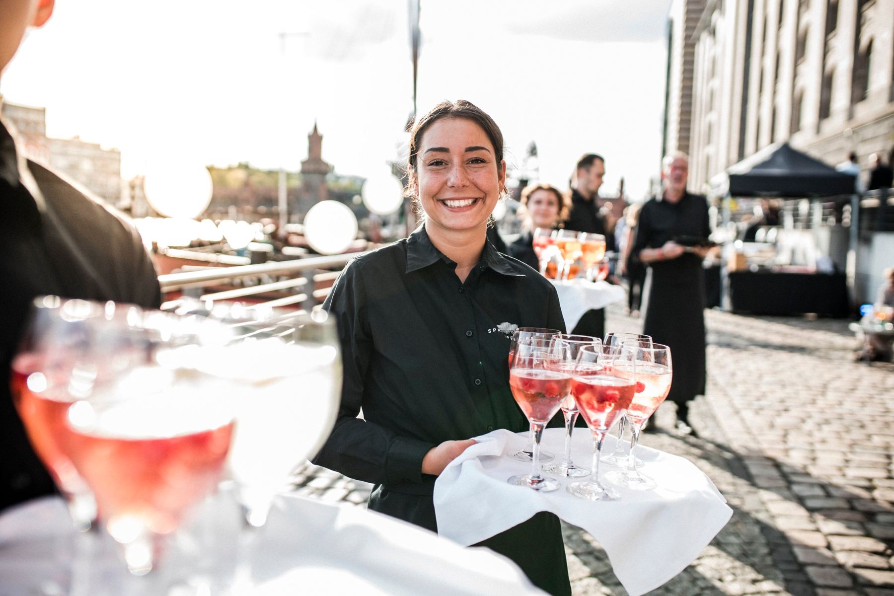 Servicemitarbeiterin serviert Aperitif auf der Uferpromenade