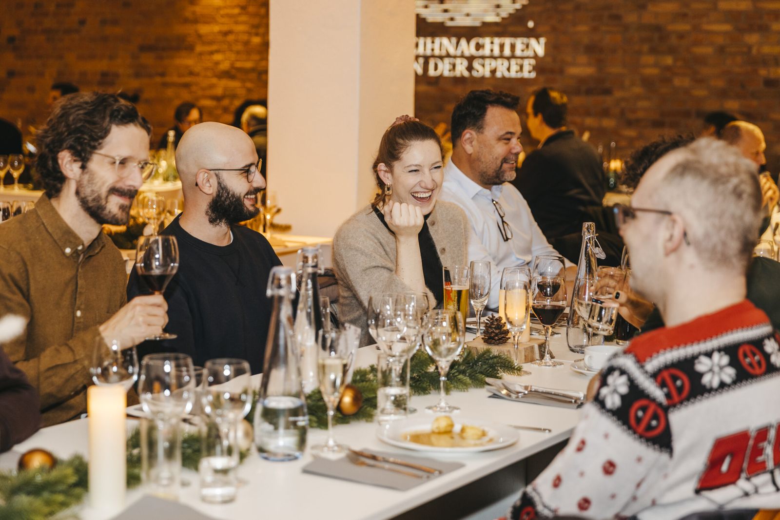 Gäste beim Indoor-Weihnachtsdinner an festlich gedeckten Tischen