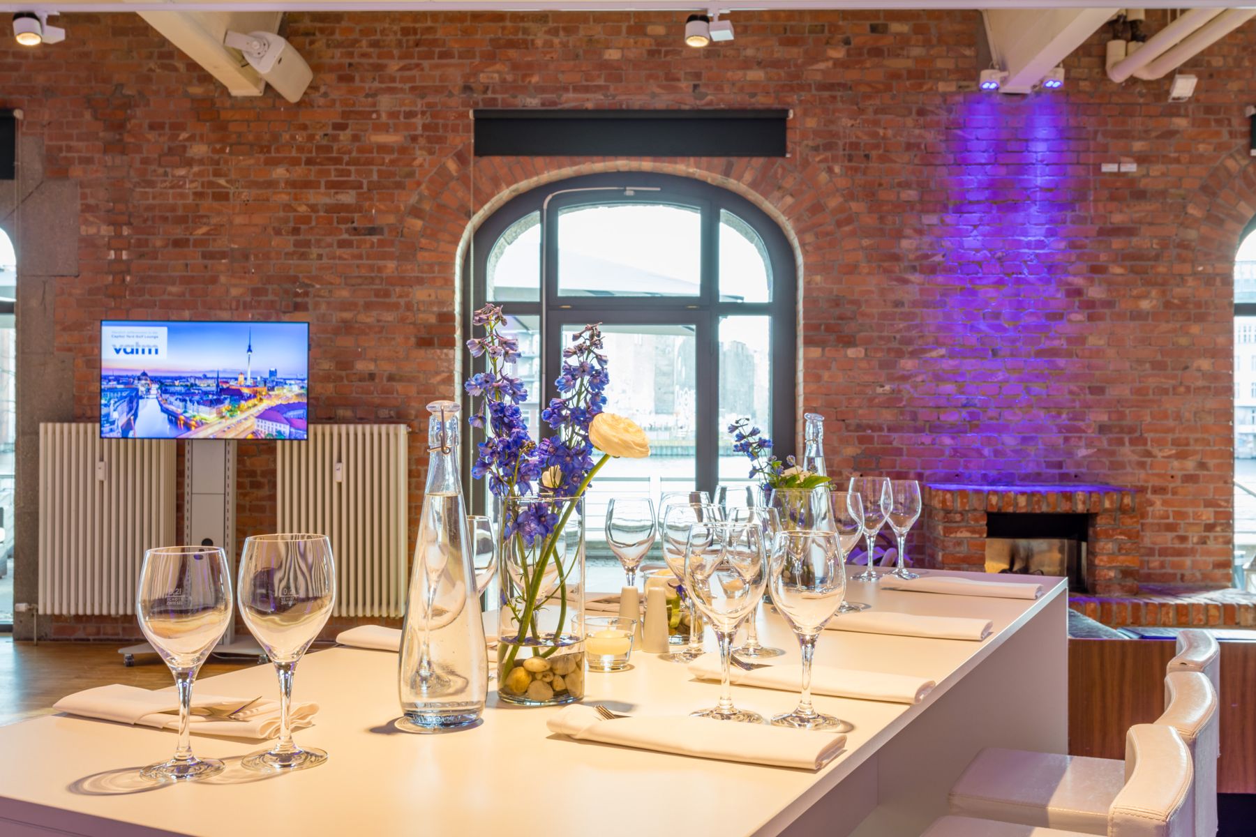 Gedeckter Tisch vor Backsteinwand und Rundbogenfenster