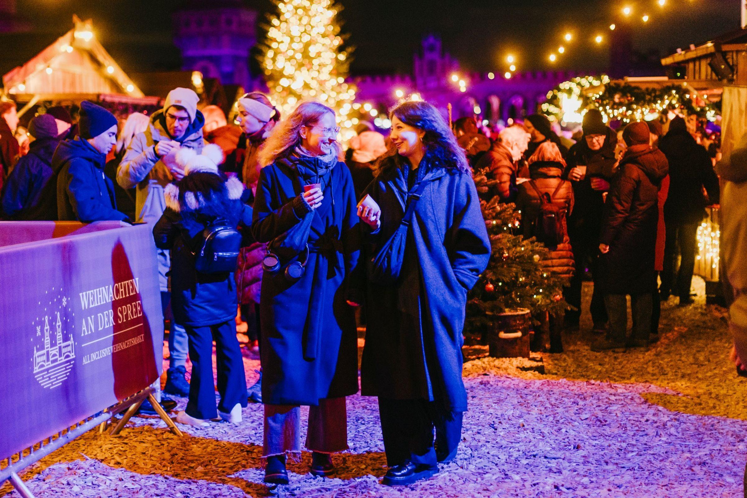 Gäste mit Glühwein auf dem Weihnachtsmarkt Weihnachten an der Spree